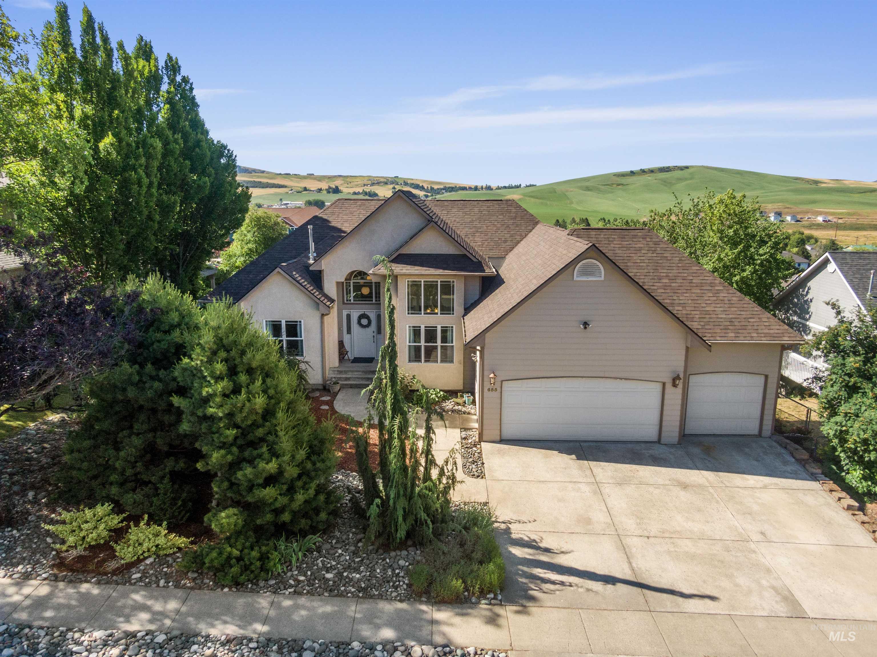 View of front facade with a garage, concrete driveway, roof with shingles, and stucco siding