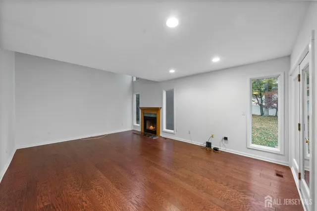 a view of an empty room with wooden floor and stairs