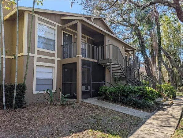 a view of a house with a small yard plants and large tree