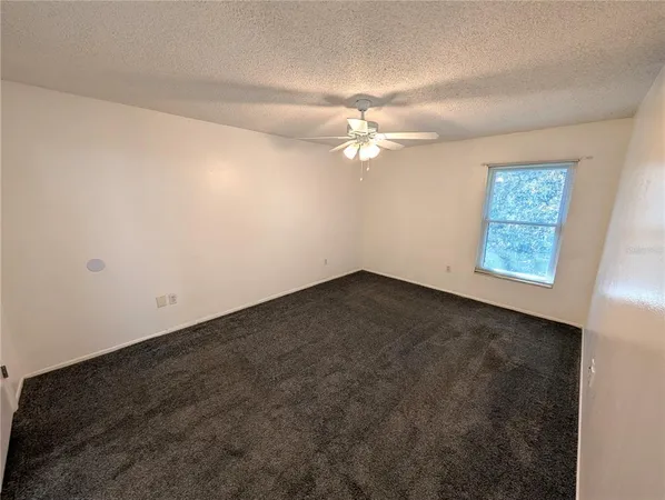 an empty room with windows and fan