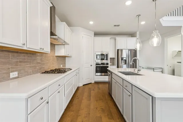 a large kitchen with kitchen island a sink a counter top space stainless steel appliances and cabinets