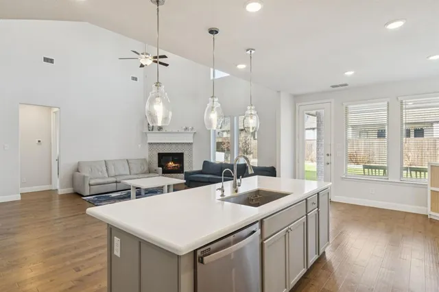 a large white kitchen with a stove a sink dishwasher and a fireplace with wooden floor