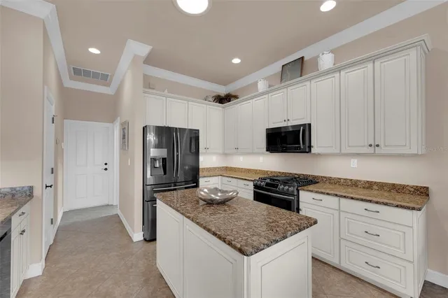 a kitchen with granite countertop stainless steel appliances a stove refrigerator and microwave with wooden floor