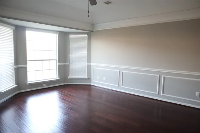 an empty room with wooden floor cabinet and windows
