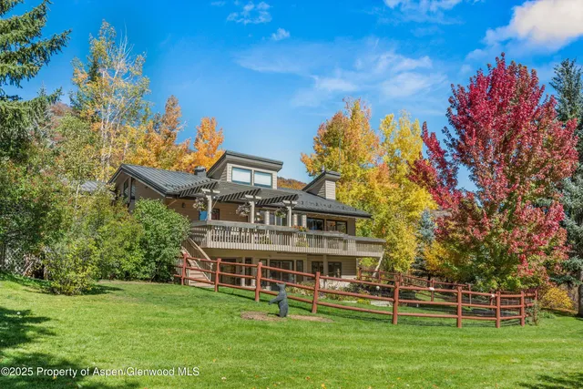 a view of a house with a big yard and large trees