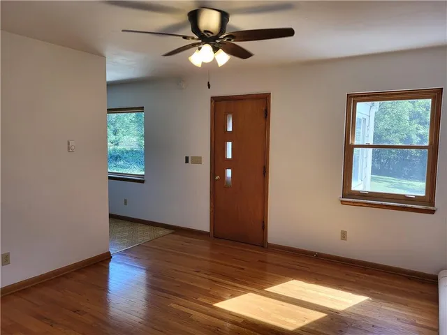 a view of an empty room with window and wooden floor