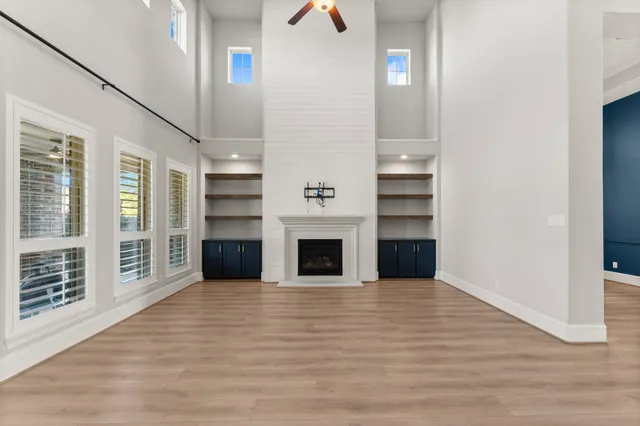 an empty room with wooden floor fireplace and windows