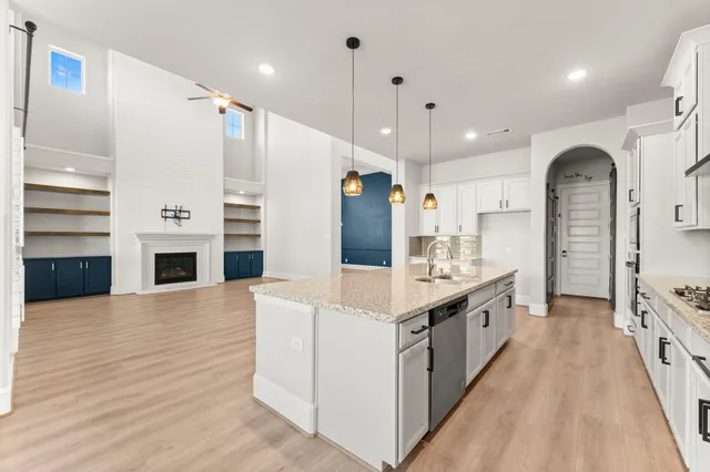 a large white kitchen with a large counter top stainless steel appliances and wooden floor