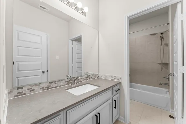 a bathroom with a granite countertop sink mirror and a bath tub