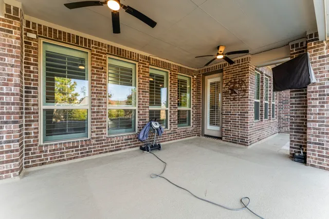 a view of an empty room with a fireplace and a ceiling fan