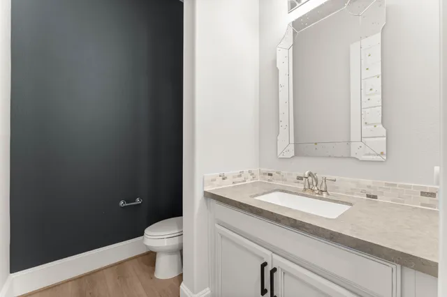 a bathroom with a granite countertop sink a toilet and a mirror