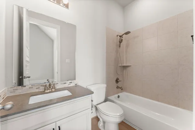 a bathroom with a granite countertop sink a toilet and a bathtub