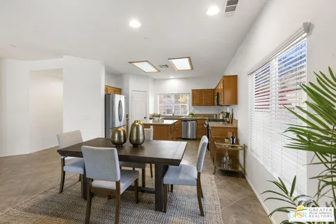a kitchen with stainless steel appliances granite countertop a table chairs and a refrigerator