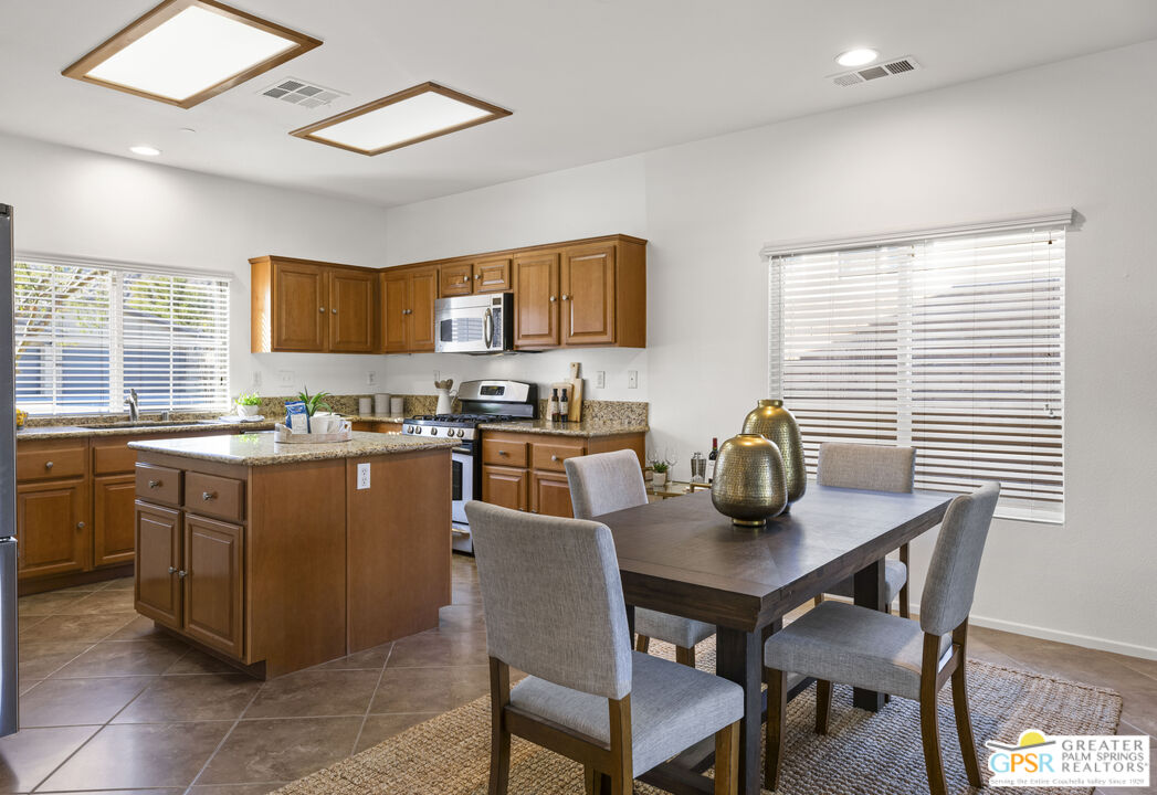 1264 Oro Ridge Palm Springs, CA 92262 - Photo 13 of 38 a kitchen with stainless steel appliances granite countertop a table chairs and a refrigerator