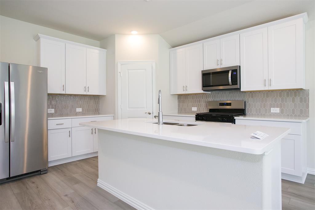 404 Castle Road Sherman, TX 75092 - Photo 4 of 25 a kitchen with appliances a sink and cabinets