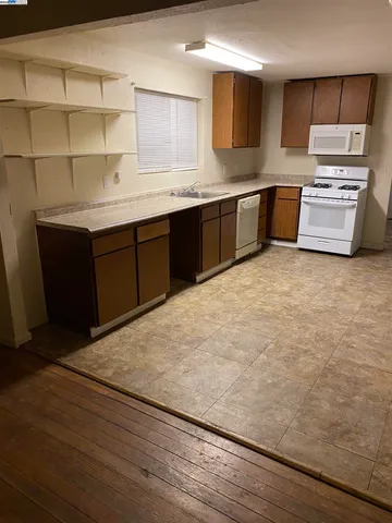 a kitchen with stainless steel appliances granite countertop a sink and cabinets with wooden floor