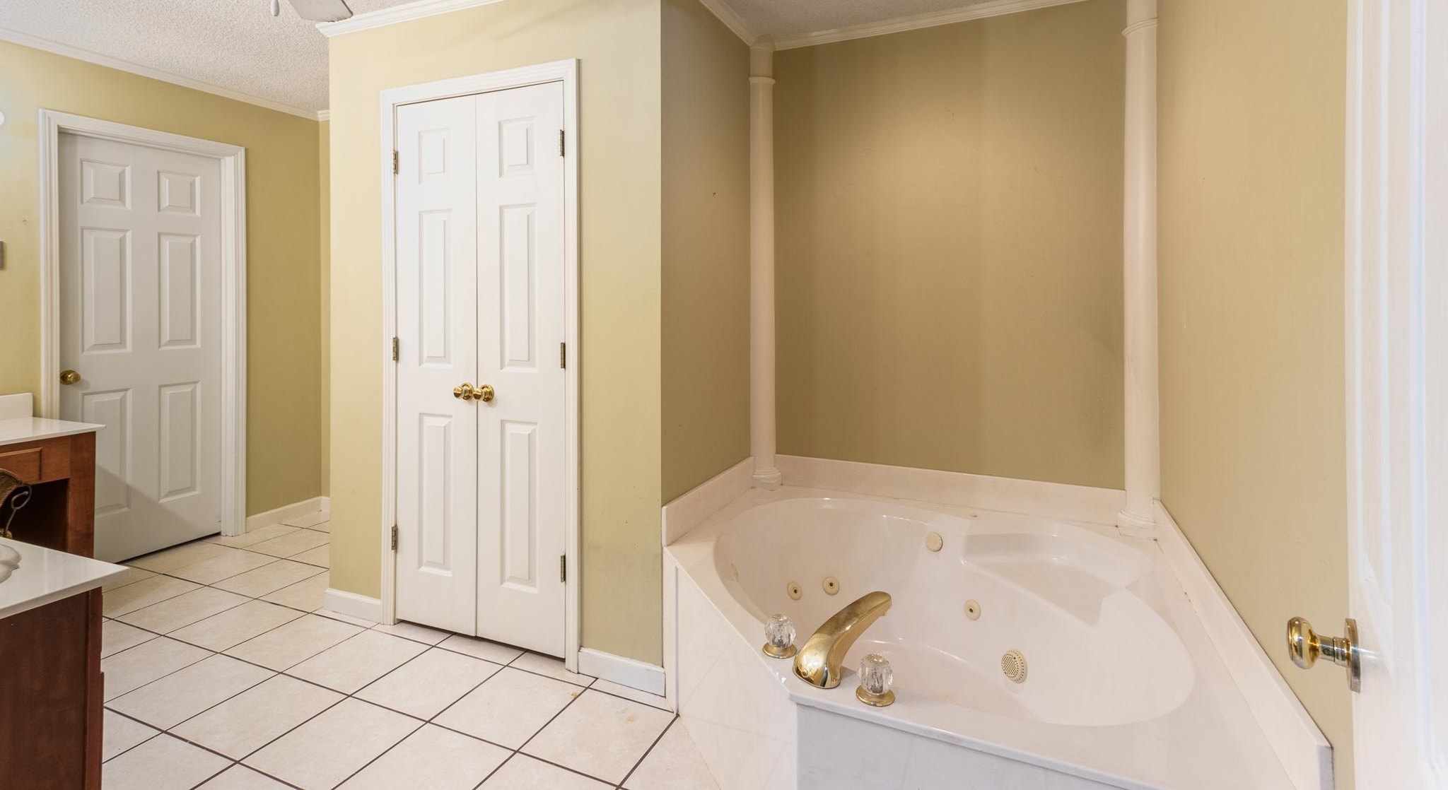 380 Woodbridge Road Somerville, TN 38068 - Photo 17 of 30 Full bathroom with a textured ceiling, vanity, light tile patterned flooring, a tub with jets, and crown molding