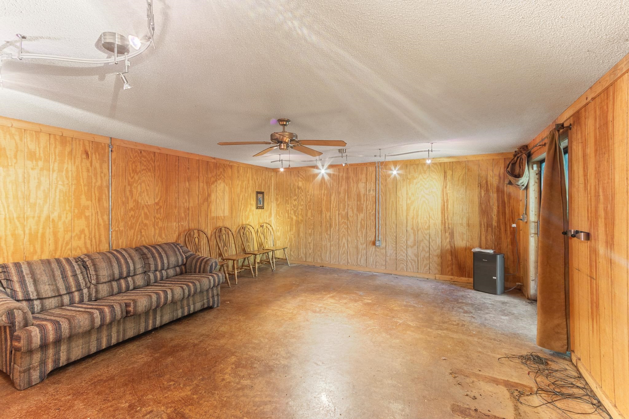 380 Woodbridge Road Somerville, TN 38068 - Photo 23 of 30 Unfurnished living room featuring concrete floors, a textured ceiling, wood walls, and a ceiling fan