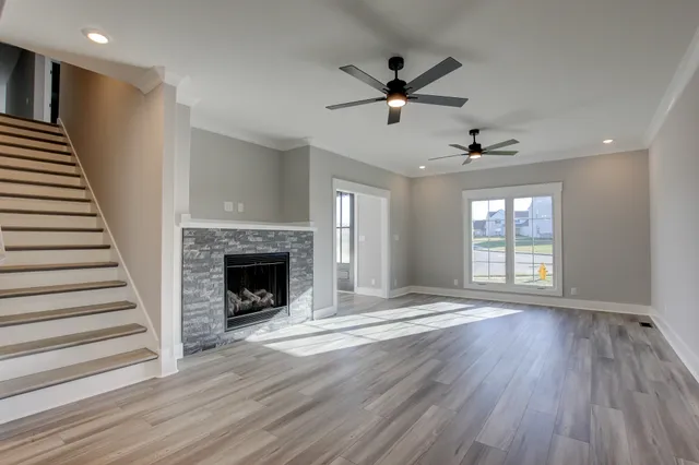 a view of an empty room with wooden floor fireplace and a window