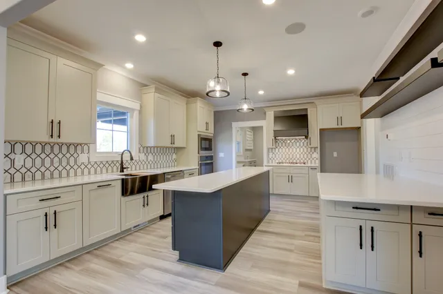 a large white kitchen with stainless steel appliances granite countertop a stove a sink dishwasher and a oven with white cabinets