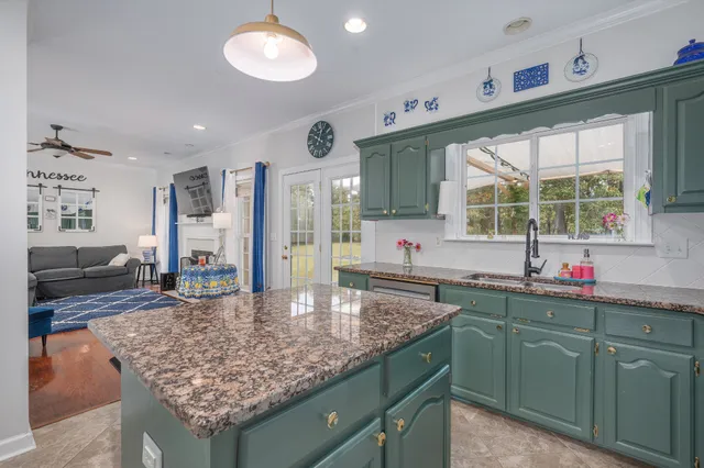 a kitchen with kitchen island granite countertop a sink window and cabinets