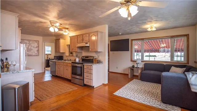 a kitchen with stainless steel appliances granite countertop a refrigerator a sink dishwasher a stove a dining table and chairs with wooden floor