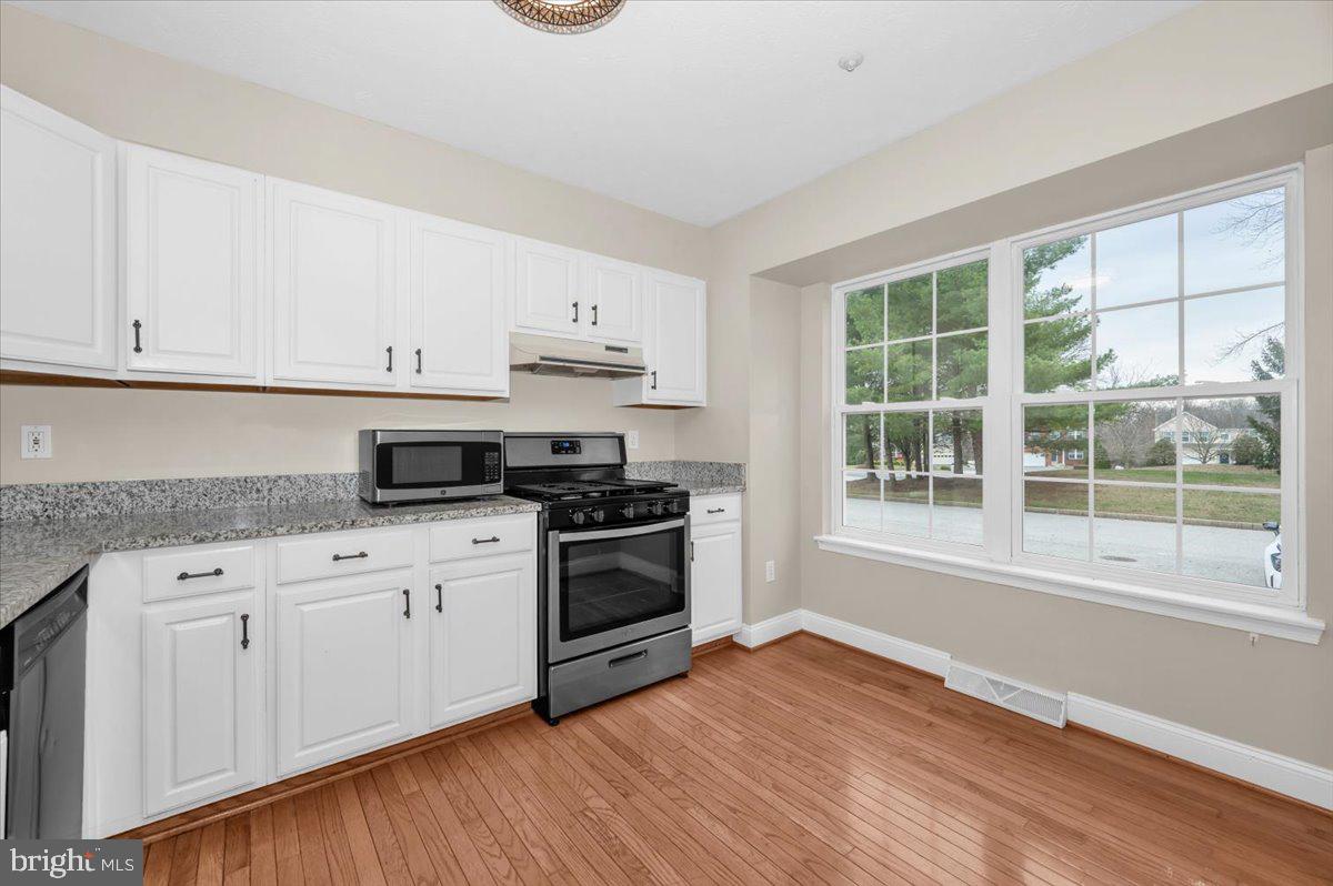 1184 Heathfield Road Sykesville, MD 21784 - Photo 10 of 56 a kitchen with granite countertop a stove a sink and white cabinets with wooden floor