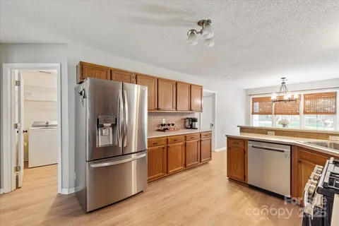 a kitchen with stainless steel appliances granite countertop a refrigerator a sink dishwasher a stove and white countertops with wooden floor