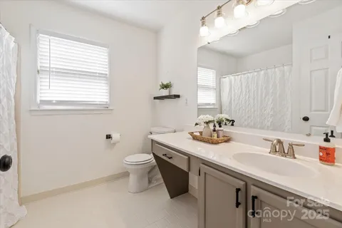 a bathroom with a granite countertop sink a toilet and a mirror