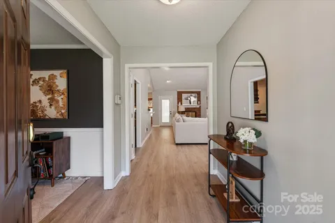 a view of a hallway with wooden floor and a living room