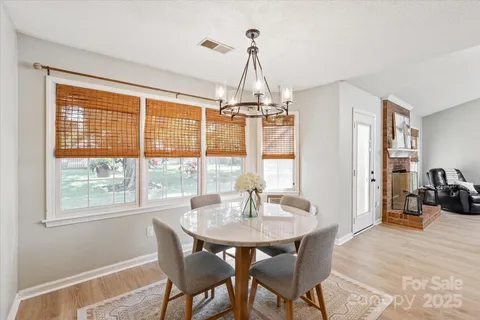 a dining room with wooden floor a chandelier a wooden table and chairs
