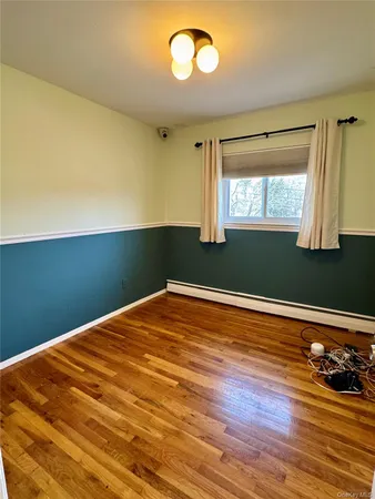 a view of empty room with window and wooden floor