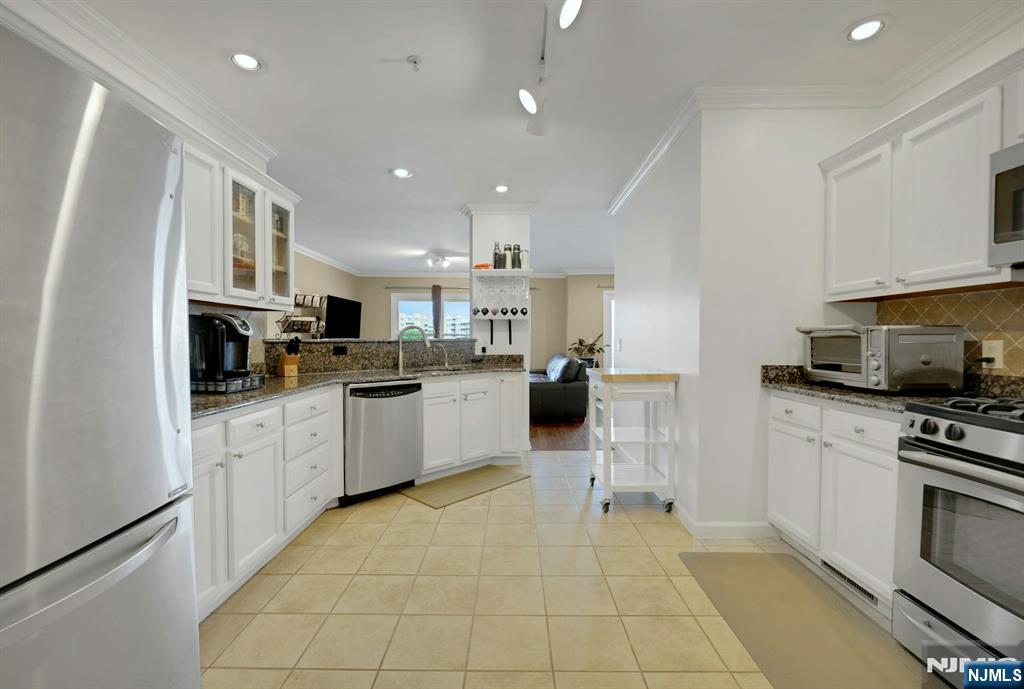 155 The Promenade Edgewater, NJ 07020 - Photo 14 of 31 a kitchen with stainless steel appliances granite countertop a refrigerator sink and cabinets