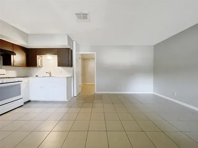 a large white kitchen with a sink a stove a microwave and cabinets