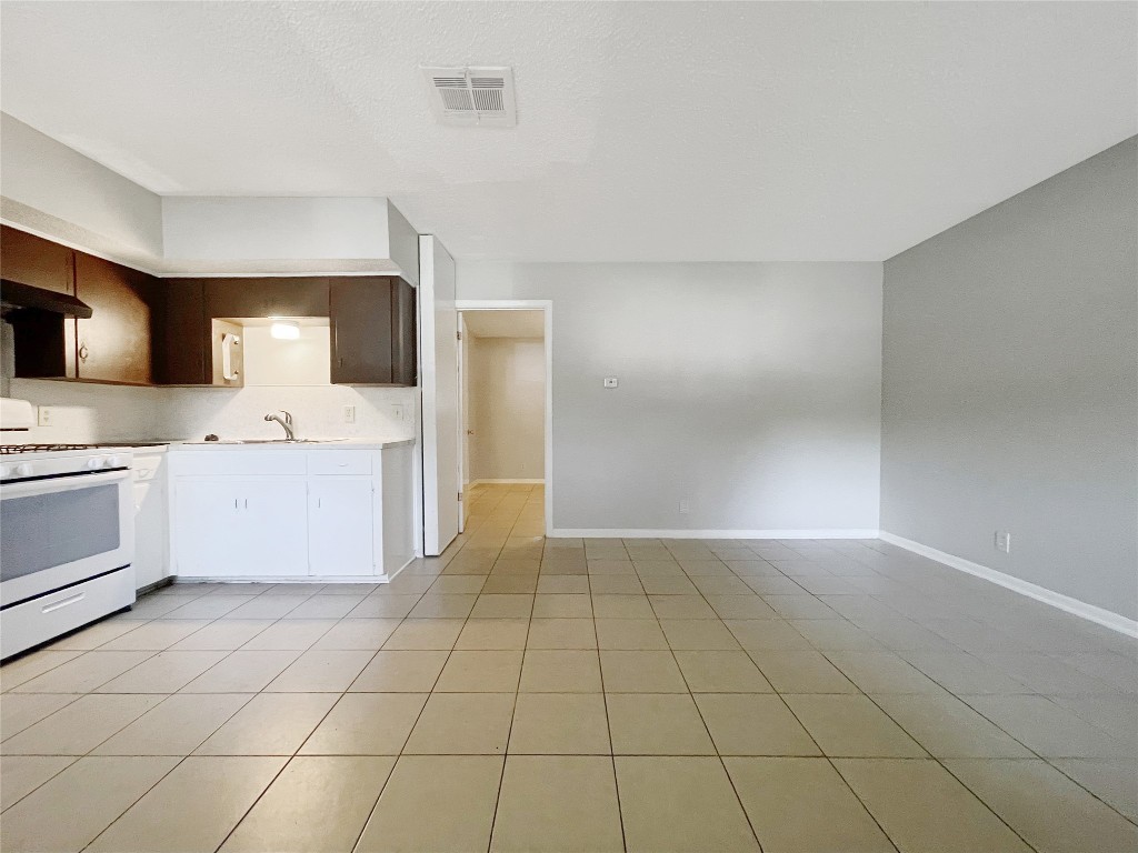 a large white kitchen with a sink a stove a microwave and cabinets