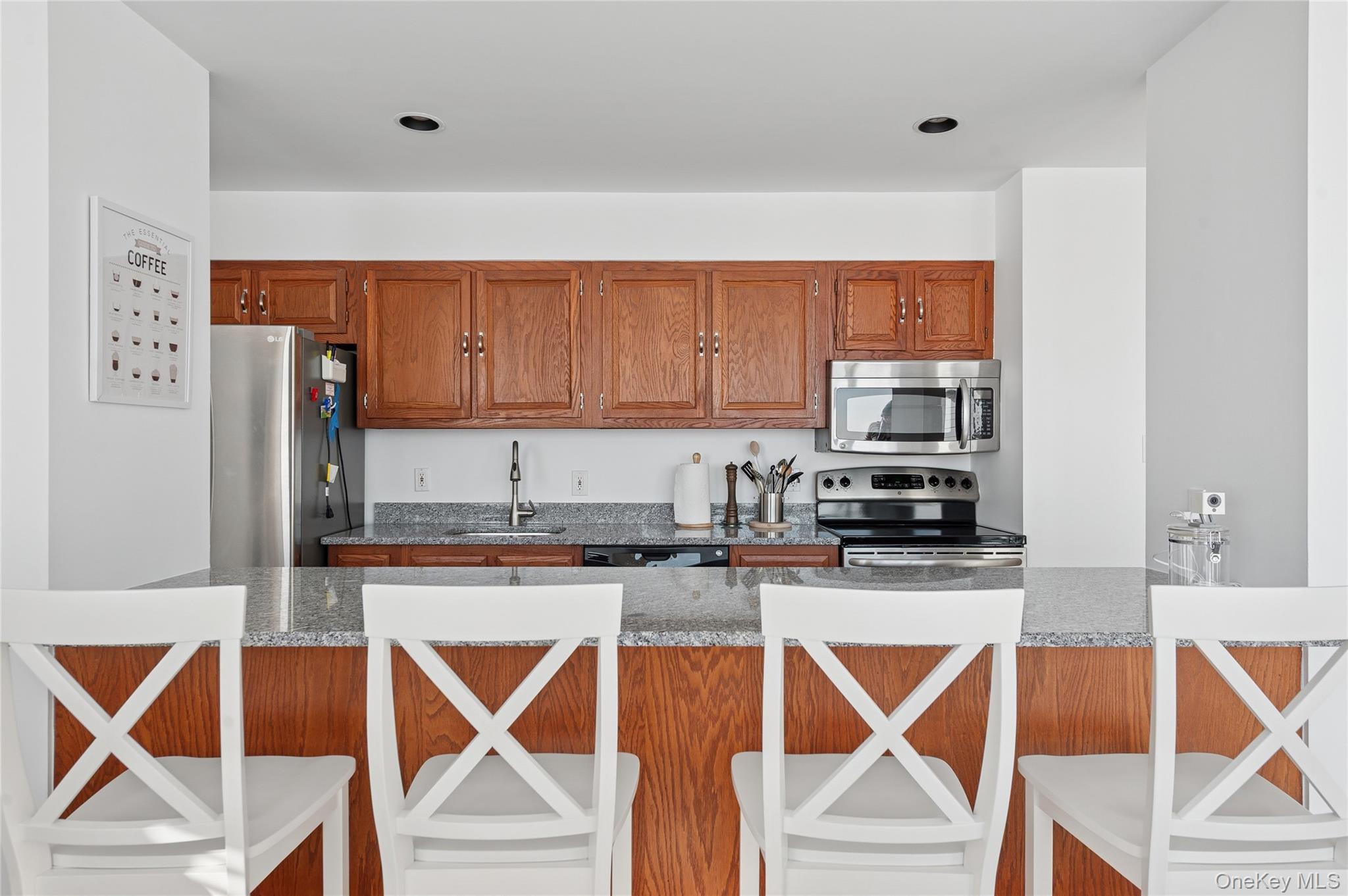 259 Dune Road, Unit 137 Westhampton Beach, NY 11978 - Photo 6 of 16 a kitchen with stainless steel appliances granite countertop a stove top oven a sink and a microwave