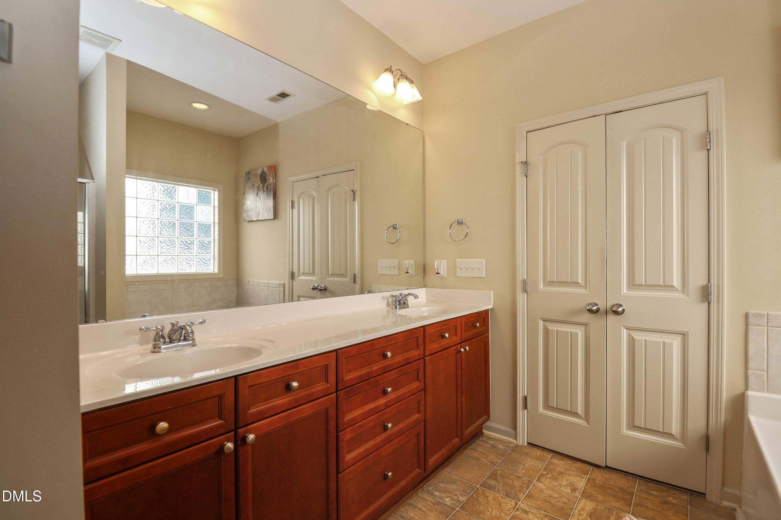 3152 Landing Falls Lane Raleigh, NC 27616 - Photo 15 of 29 a spacious bathroom with a double vanity sink a large mirror and shower