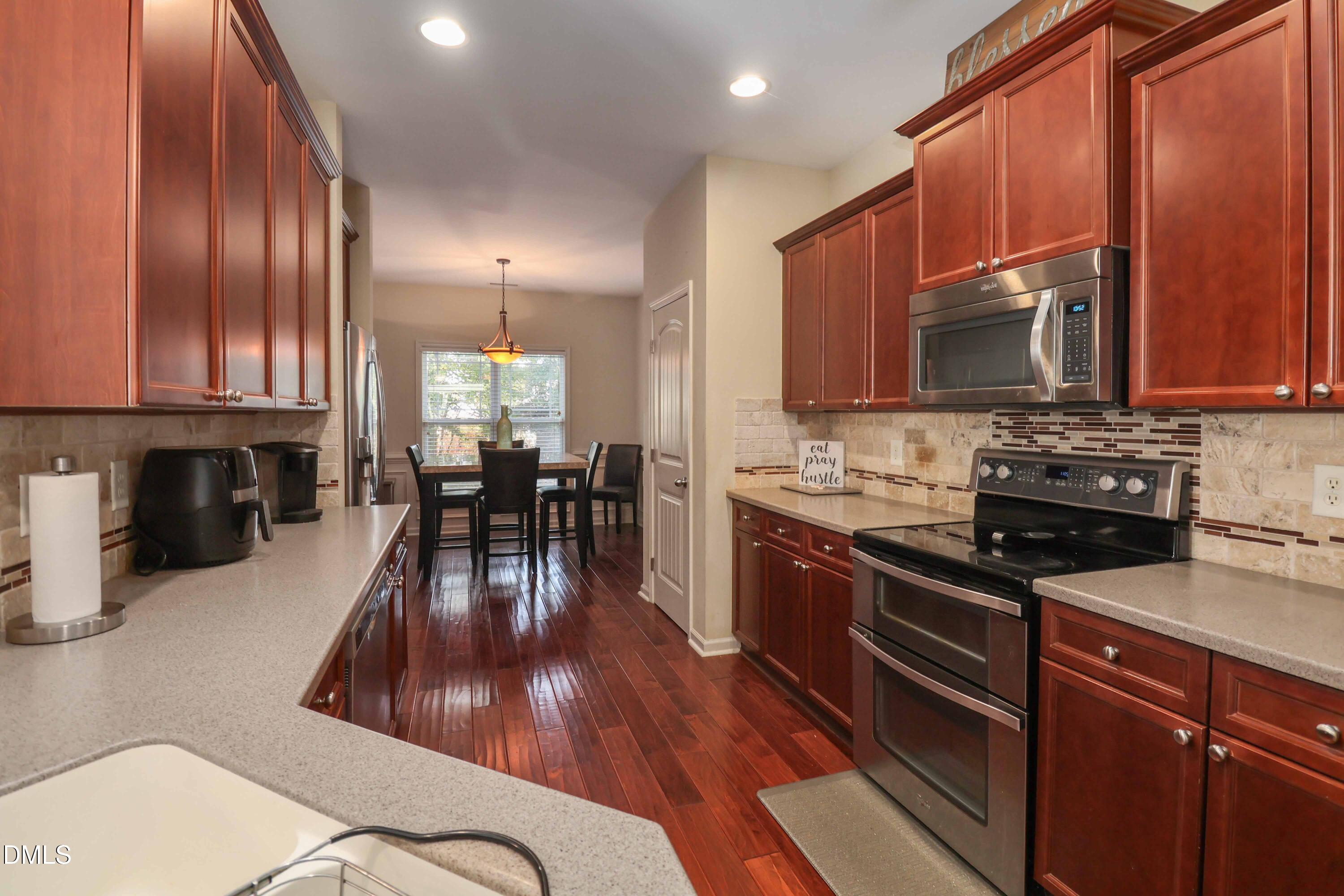 3152 Landing Falls Lane Raleigh, NC 27616 - Photo 9 of 29 a kitchen with stainless steel appliances granite countertop wooden cabinets a stove top oven a sink and dishwasher