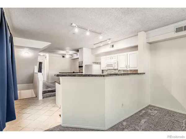 a view of a kitchen with refrigerator and white cabinets