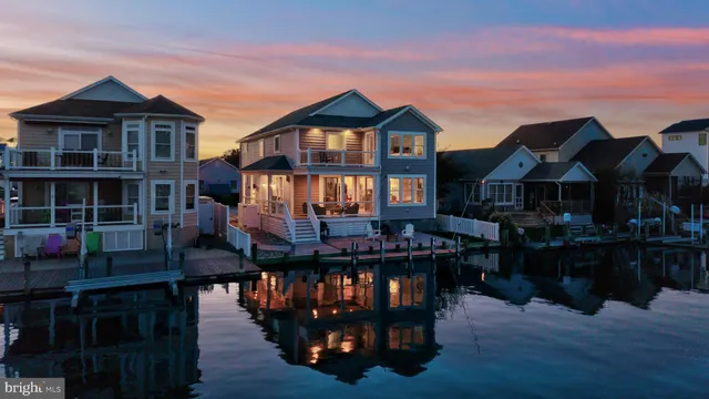 a front view of a house with wooden deck and furniture