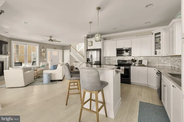 a large white kitchen with cabinets a sink a window and stainless steel appliances