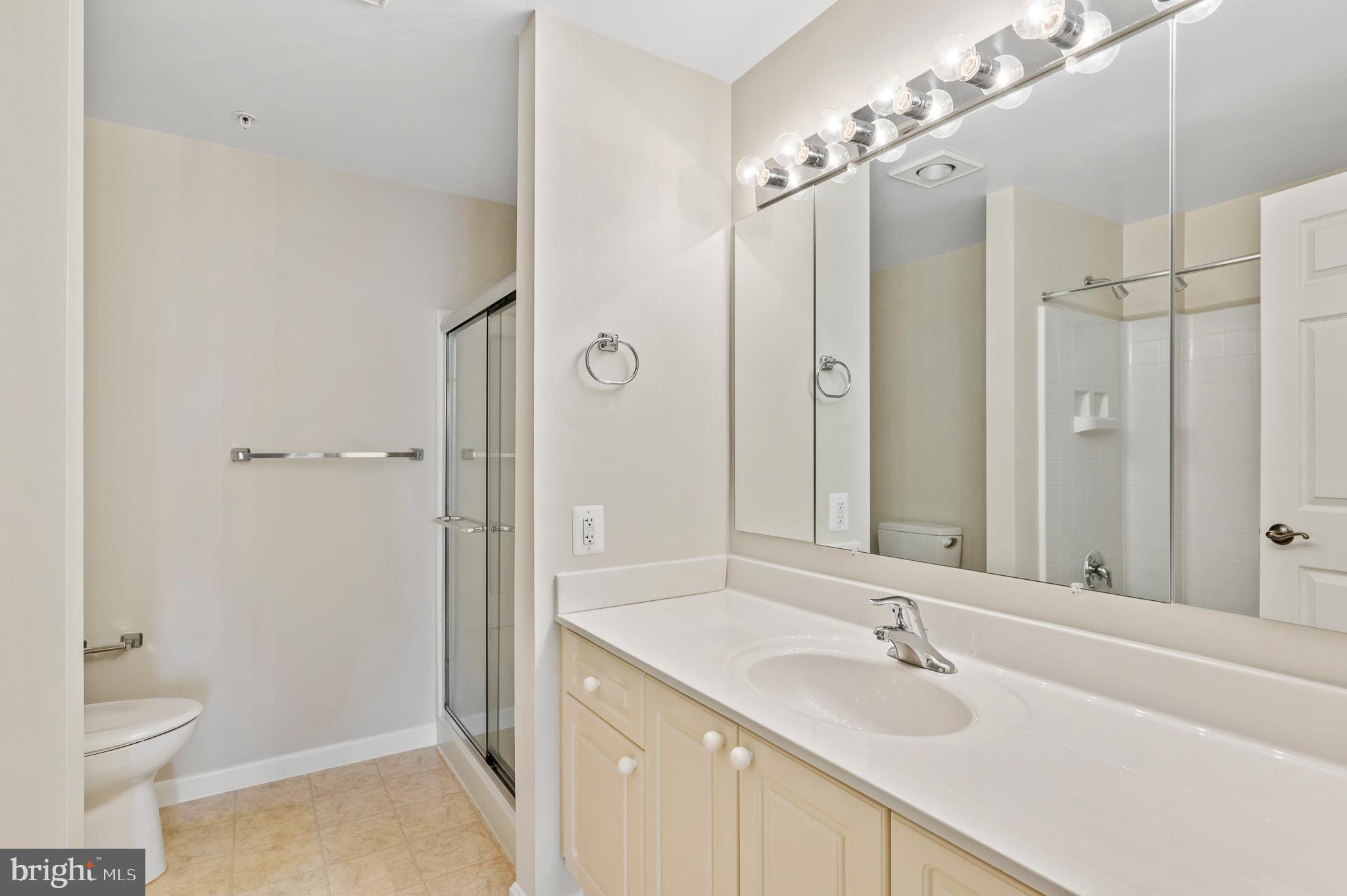 19355 Cypress Ridge Terrace, Unit 821 Leesburg, VA 20176 - Photo 23 of 27 a bathroom with a granite countertop sink toilet a shower and a mirror