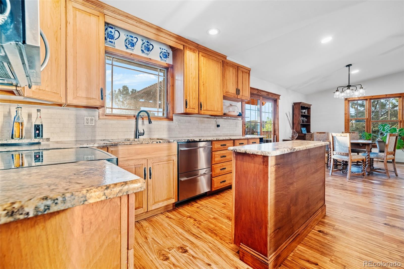 8440 South Warhawk Road Conifer, CO 80433 - Photo 19 of 48 a kitchen with kitchen island granite countertop wooden floors and a view of living room