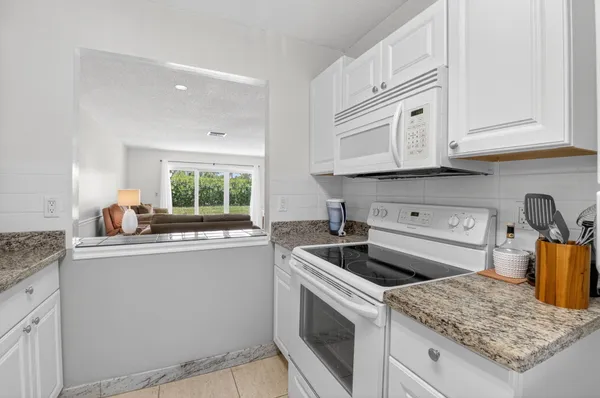 a kitchen with granite countertop white cabinets and white appliances
