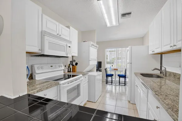 a kitchen with granite countertop a sink a stove and cabinets