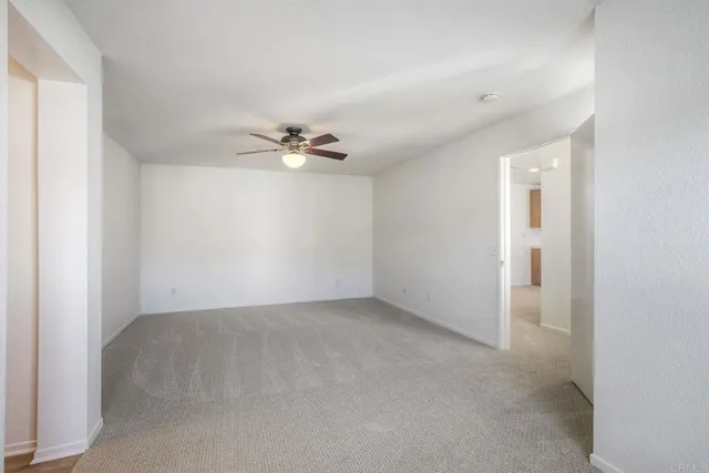 a view of an empty room with a chandelier fan