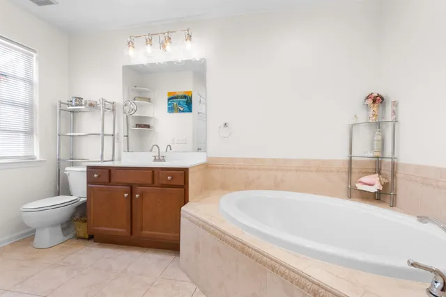 a bathroom with a bathtub sink vanity mirror and toilet
