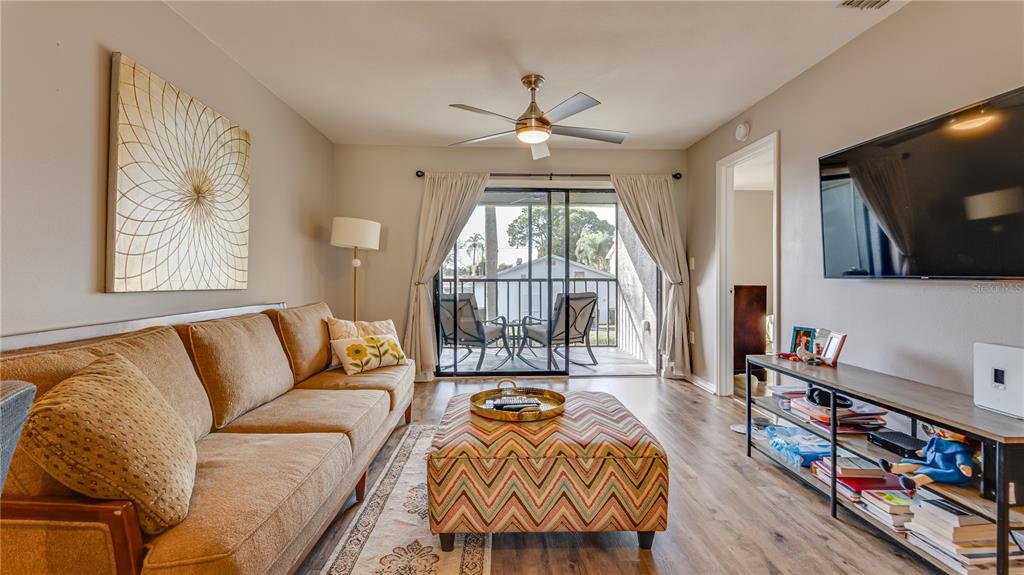 6145 113th Street, Unit 415 Seminole, FL 33772 - Photo 11 of 35 a living room with furniture a flat screen tv and a floor to ceiling window