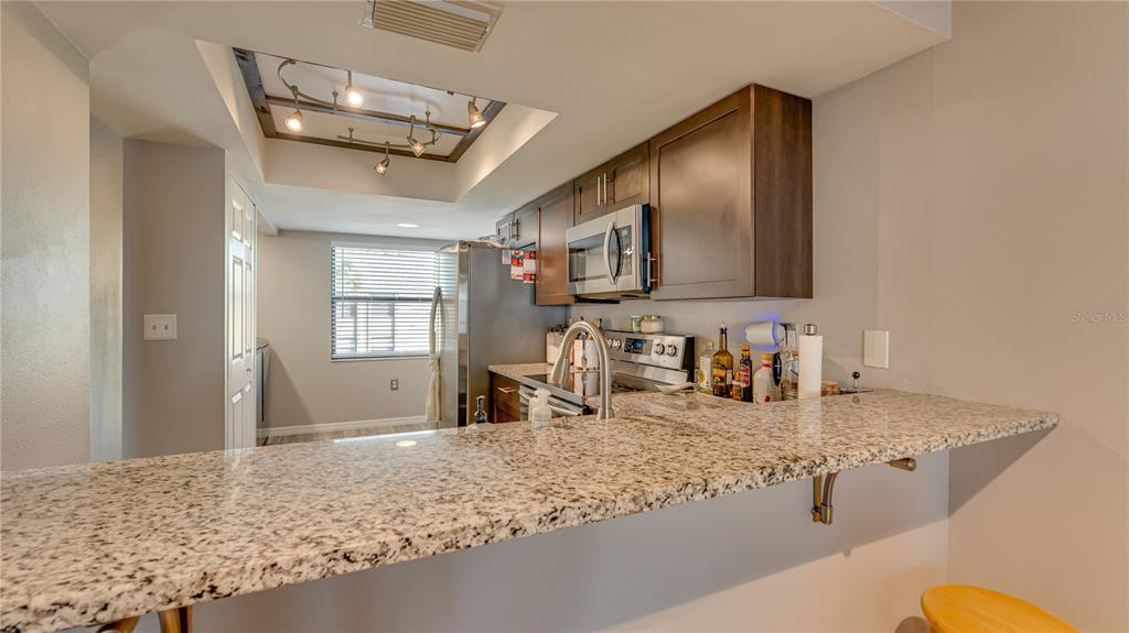 6145 113th Street, Unit 415 Seminole, FL 33772 - Photo 14 of 35 a kitchen with granite countertop a sink a stove counter top space and cabinets