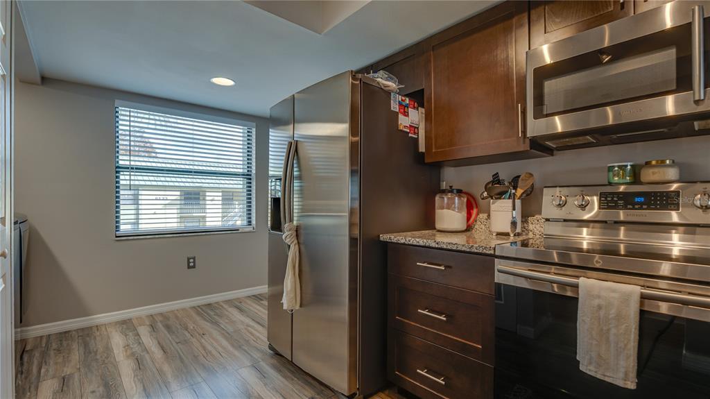 6145 113th Street, Unit 415 Seminole, FL 33772 - Photo 16 of 35 a kitchen with stainless steel appliances granite countertop a sink cabinets and wooden floor